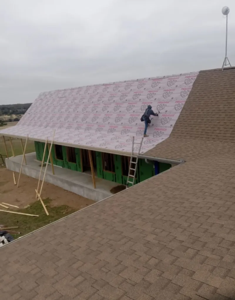 Worker preparing underlayment for a metal roof installation in Wailuku